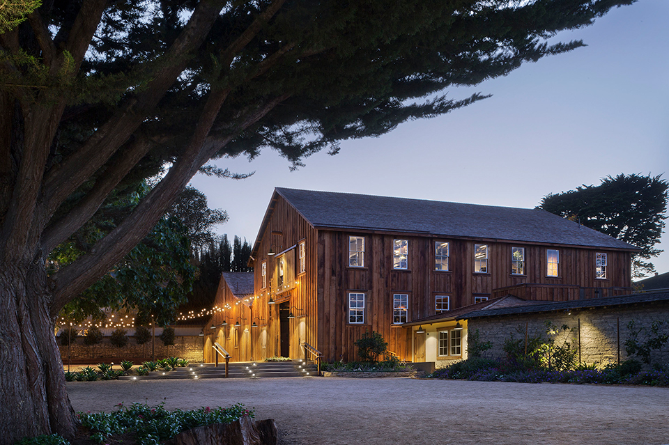 Evening exterior shot of the barn at Cooper-Molera in the distant illuminated by string of lights