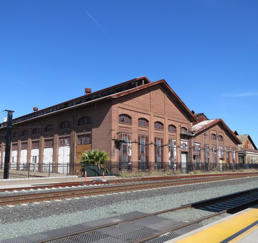 Exterior image across train tracks of two red buildings
