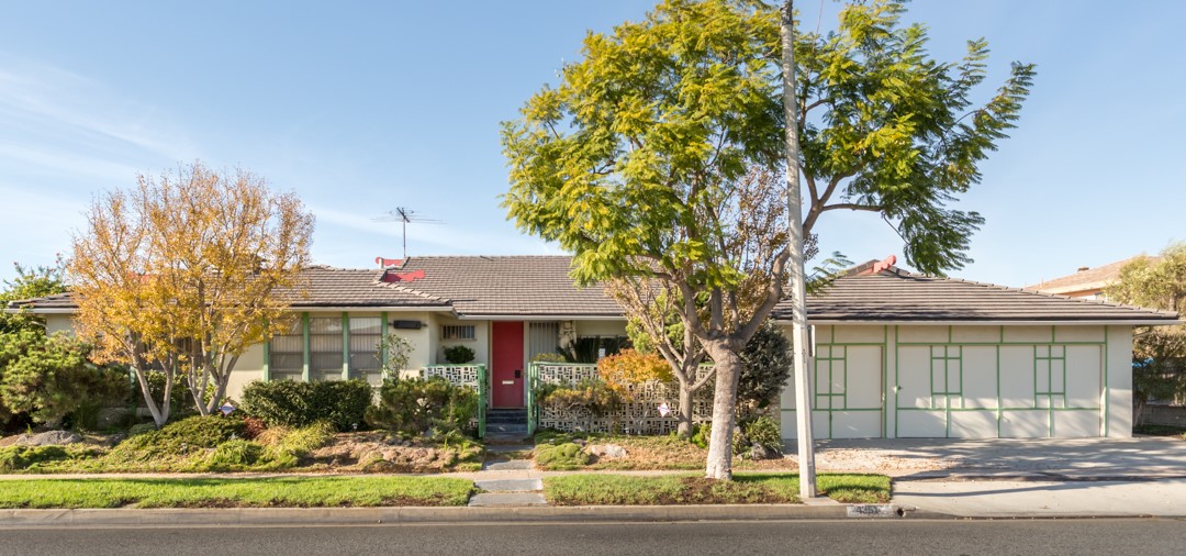 a green home with a red door, adorned surrounded by trees